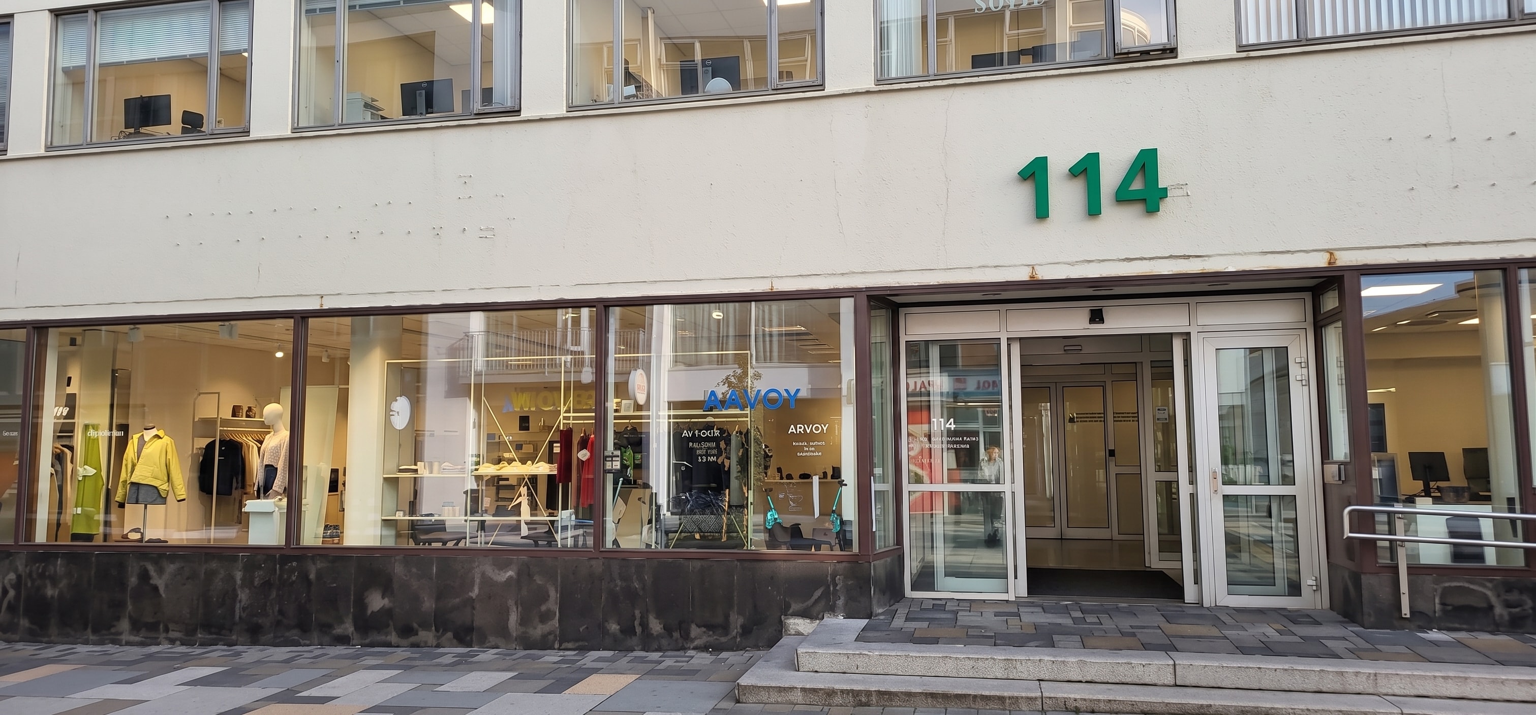 The glazed storefront and green 114 building number at Laugavegur 114 in Reykjavík.
