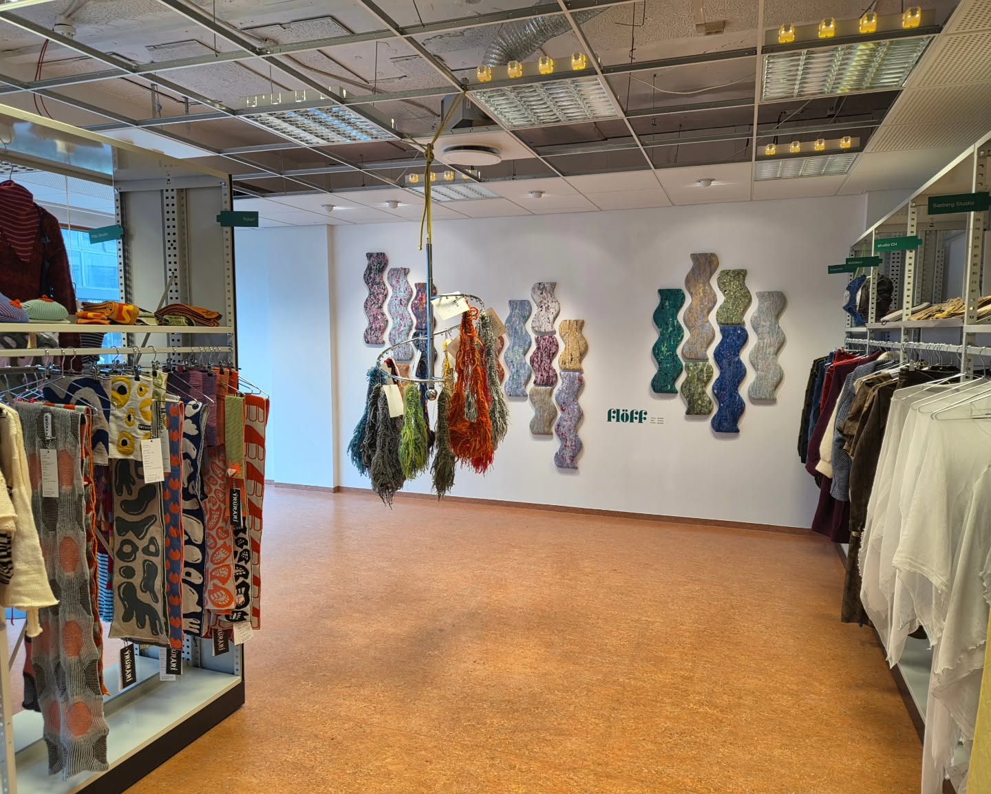 Clothing and textiles frame the colourful Flöff artwork on the rear wall of 114.