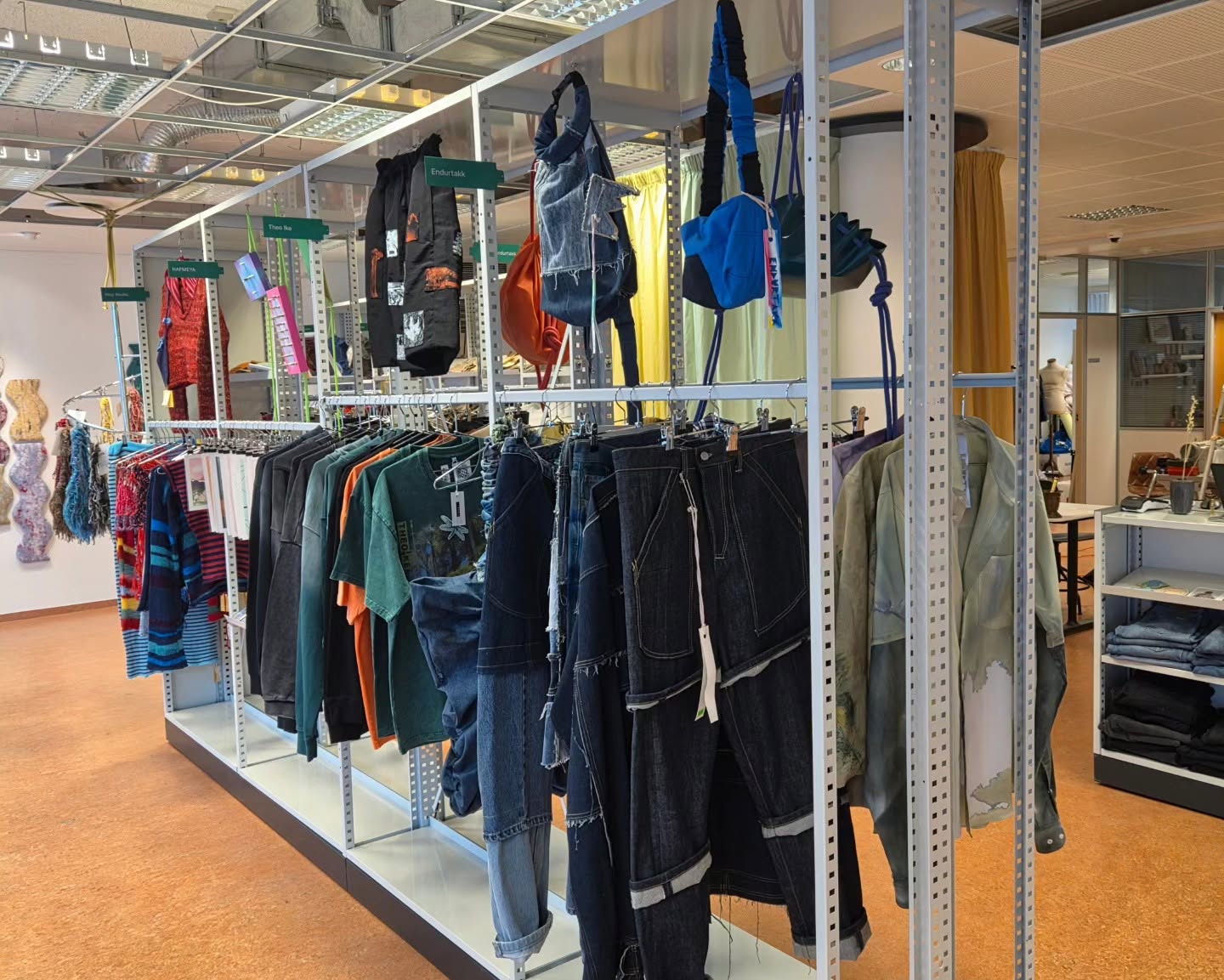 Denim, clothing and handmade bags displayed on open metal racks.