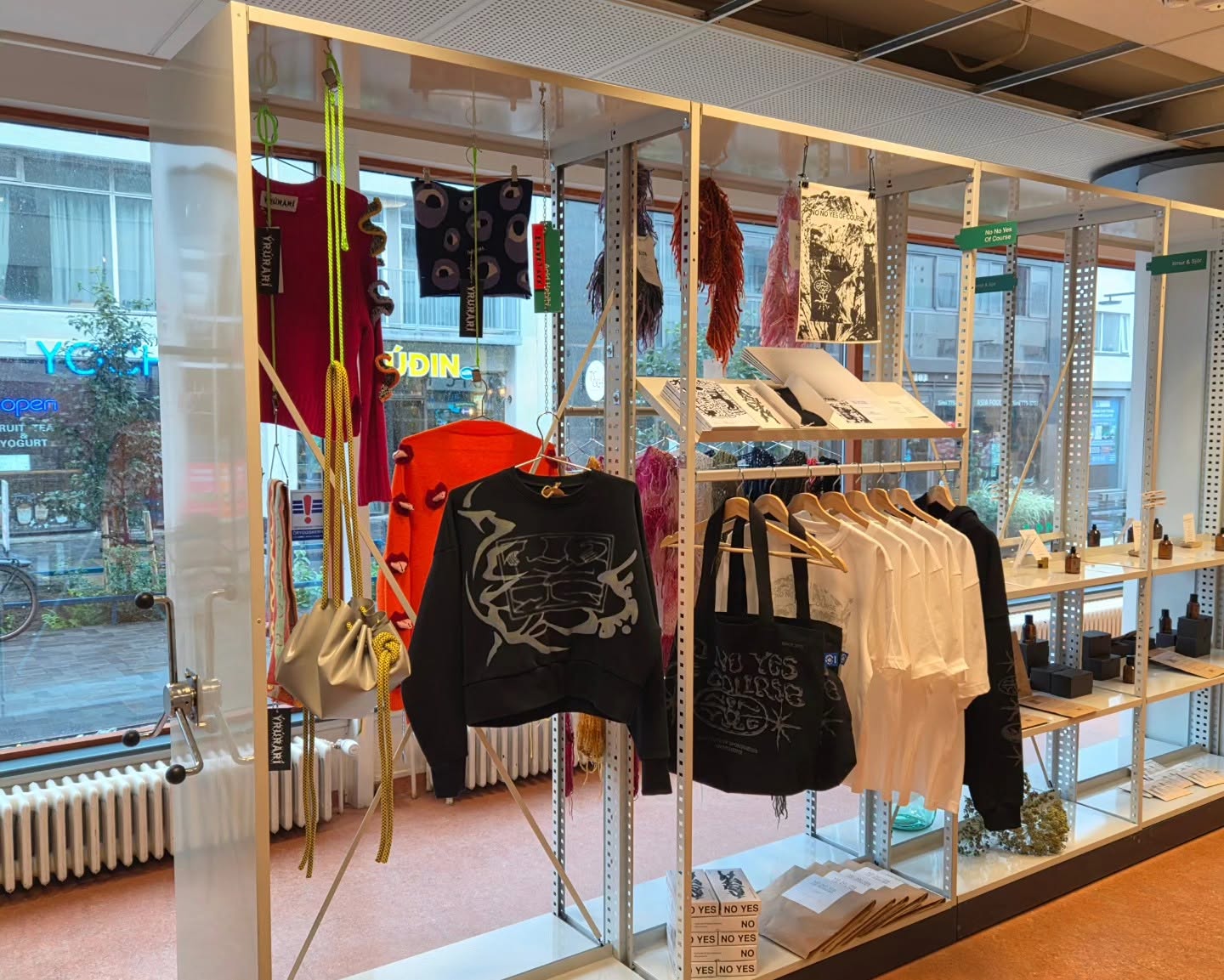 Clothing, bags, printed artwork and small objects in the window-side display.